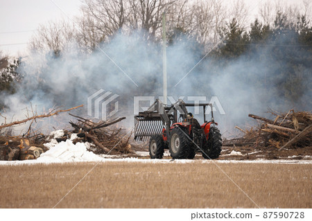 Tractor Moves Brush During a Controlled Burn on a Farm Property to Increase Arable Land Tractor Moves Brush During a Controlled Burn on a Farm Property to Increase Arable Land 87590728