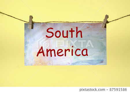South America text written on paper suspended from a rope on a yellow background 87591586