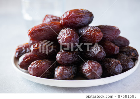 Close up of Medjoul dates in a white plate on a gray background. 87591593
