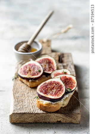 Two sandwiches with figs, thyme on a wooden board on textured background Two sandwiches with figs, thyme on a wooden board on textured background 87594513