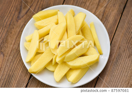 fresh raw potato wedges, chopped potatoes for cooked food on white plate 87597081