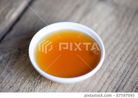 fish sauce on white bowl on wooden background, fish sauce obtained from fermentation fish or small aquatic animal, fermented foods 87597093