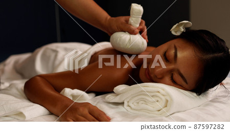 Young Asian woman receiving back massage with Thai herbal compress ball at spa salon by professional masseuse, Spa treatment and thai massage concept Young Asian woman receiving back massage with Thai herbal compress ball at spa salon by professional masseuse, Spa treatment and thai massage concept 87597282