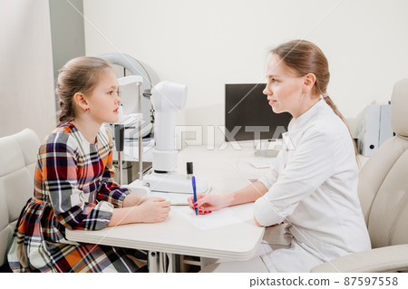 doctor interviews little girl before being examined in ophthalmologist's office. doctor interviews little girl before being examined in ophthalmologist's office. 87597558