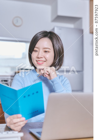 A young woman looking at her pension book and thinking about the future A young woman looking at her pension book and thinking about the future 87597923