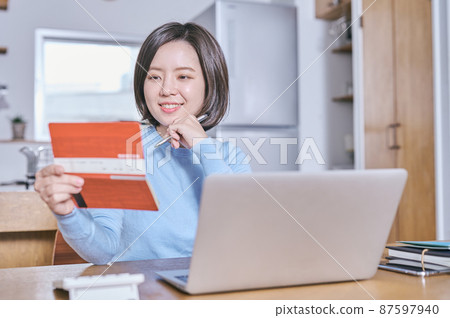 A young woman looking at her bankbook and thinking about the future 87597940