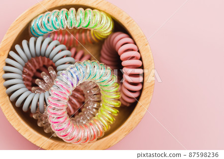 The wooden bowl of spiral hair rubber bands on pink background The wooden bowl of spiral hair rubber bands on pink background 87598236