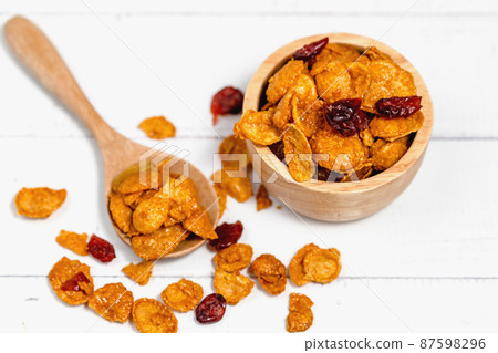 The wooden bowl of caramel cornflakes with raisins on white background 87598296