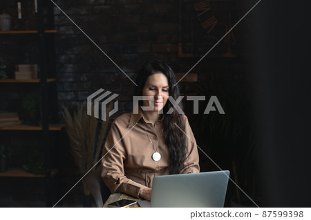 Attractive business woman with a laptop in the office at work. The concept of remote work, work for yourself. Front view. 87599398