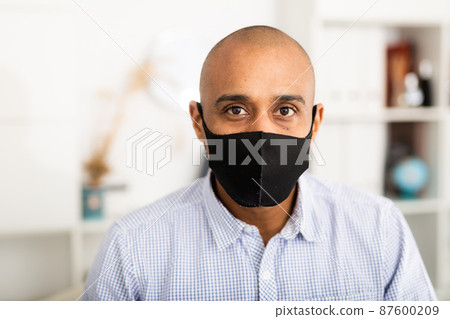 Businessman in protective mask makes notes in document 87600209