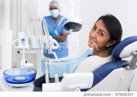 Woman sitting in dental chair after teeth cure giving thumb up Woman sitting in dental chair after teeth cure giving thumb up 87600307