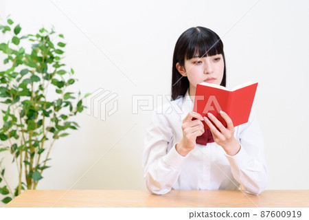 打開筆記本查看的女高中生。 打開筆記本查看的女高中生。 87600919