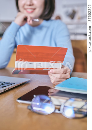 一個年輕女人看著她的存摺,思考著未來 一個年輕女人看著她的存摺,思考著未來 87602203