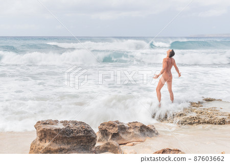 Carefree naked man enjoying freedom on nude beach 87603662