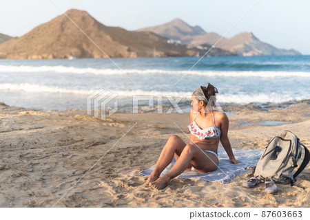Woman in swimsuit resting on sandy beach near sea 87603663
