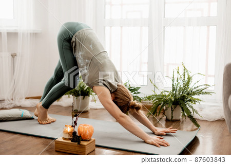 Beautiful young woman doing exercises and doing yoga at home 87603843