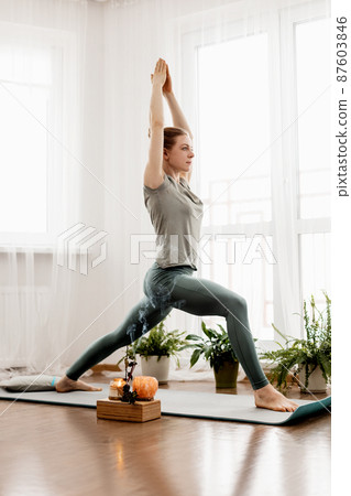 Beautiful young woman doing exercises and doing yoga at home 87603846