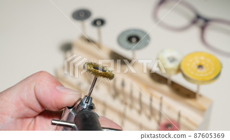 An optician technician polishes the frame of glasses. A professional optician fixes glasses. An optician technician polishes the frame of glasses. A professional optician fixes glasses. 87605369