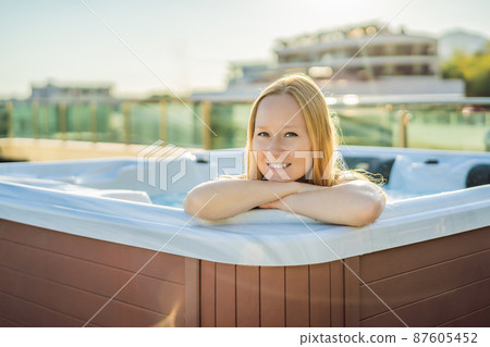 Portrait of young carefree happy smiling woman relaxing at hot tub during enjoying happy traveling moment vacation life against the background of green big mountains Portrait of young carefree happy smiling woman relaxing at hot tub during enjoying happy traveling moment vacation life against the background of green big mountains 87605452