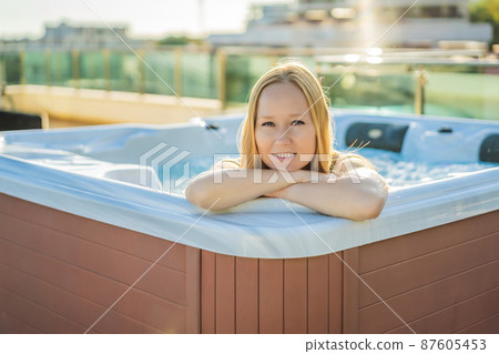 Portrait of young carefree happy smiling woman relaxing at hot tub during enjoying happy traveling moment vacation life against the background of green big mountains Portrait of young carefree happy smiling woman relaxing at hot tub during enjoying happy traveling moment vacation life against the background of green big mountains 87605453