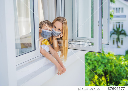 Extremly tired Mother and son looking out the window, home alone. self-isolation at home, quarantine due to pandemic COVID 19. Mental health problems in self-isolation at home, quarantine, isolation 87606577