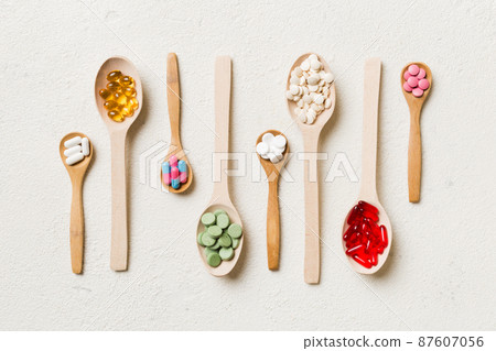 Top view Variety of vitamin and mineral pills in wooden spoon on Colored background. Top view of assorted pharmaceutical medicine pills. Dietary supplement healthcare product Top view Variety of vitamin and mineral pills in wooden spoon on Colored background. Top view of assorted pharmaceutical medicine pills. Dietary supplement healthcare product 87607056
