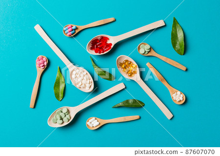 Top view Variety of vitamin and mineral pills in wooden spoon on Colored background. Top view of assorted pharmaceutical medicine pills. Dietary supplement healthcare product Top view Variety of vitamin and mineral pills in wooden spoon on Colored background. Top view of assorted pharmaceutical medicine pills. Dietary supplement healthcare product 87607070
