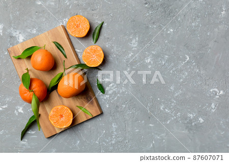Many fresh ripe mandarin with green leaves on colored background, top view, space for text Many fresh ripe mandarin with green leaves on colored background, top view, space for text 87607071