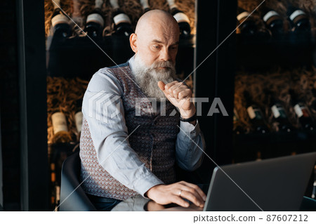 business owner of a liquor store sitting in front of an open laptop . business owner of a liquor store sitting in front of an open laptop . 87607212