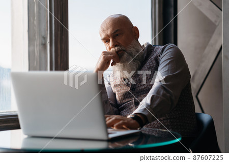 elderly liquor store owner works on a laptop . elderly liquor store owner works on a laptop . 87607225