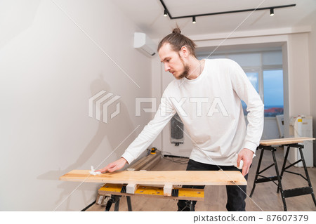 the carpenter covers the wood with oil with a napkin.  87607379