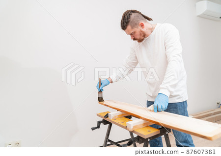 the carpenter covers the wood with oil with a brush.  87607381
