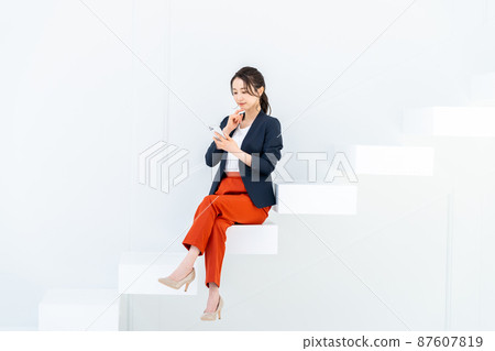 Business woman looking at a smartphone on the stairs Business woman looking at a smartphone on the stairs 87607819