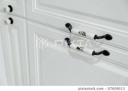 Extremely close-up detail of vintage white cabinet, original ceramic handles, selective focus, copy space Extremely close-up detail of vintage white cabinet, original ceramic handles, selective focus, copy space 87609013
