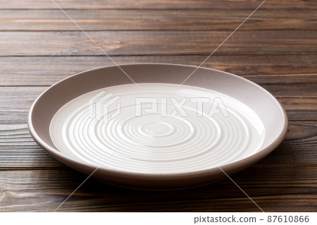 Perspective view of empty light plate on wooden background. Empty space for your design Perspective view of empty light plate on wooden background. Empty space for your design 87610866