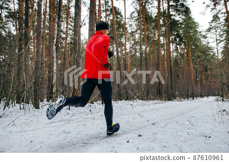 male runner running winter race in forest 87610961