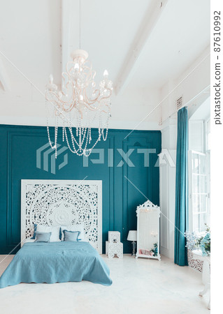 Beautiful luxury classic clean interior bedroom in white and deep blue color with king-size bed and chic carved furniture. Bright modern stylish interior bedroom and living room in minimalist style 87610992
