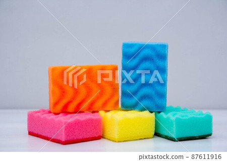Multicolored sponges for cleaning and washing dishes on a white table. Space for text Multicolored sponges for cleaning and washing dishes on a white table. Space for text 87611916