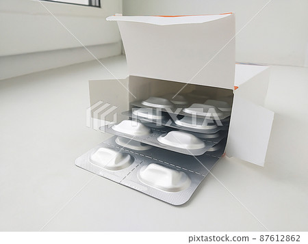 Paper packing with medical tablet rests upon window Paper packing with medical tablet rests upon window 87612862