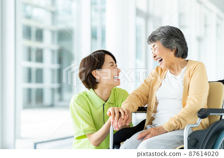 坐輪椅的高級婦女和中級護理人員 87614020