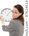 Young woman holding a clock. 87614614