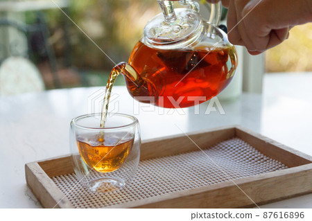 Close up of the hand pouring green tea from glass kettle to small cup 87616896