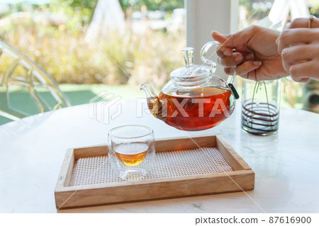 Close up of the hand pouring green tea from glass kettle to small cup 87616900