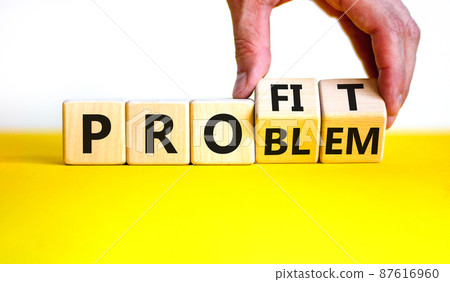 Solving a problem and making profit symbol. Businessman turns wooden cubes, changes the word 'problem' to 'profit'. Beautiful white background. Business, problem to profit concept. Copy space. 87616960