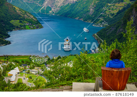 Tourist enjoying fjord Geiranger from viewpoint Tourist enjoying fjord Geiranger from viewpoint 87618149