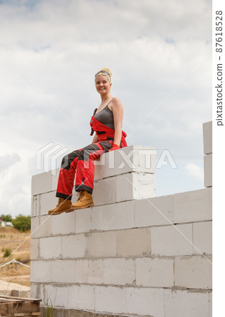 Woman in dungarees taking break on construction site Woman in dungarees taking break on construction site 87618528