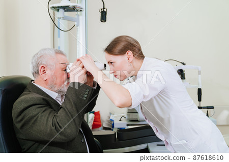 ophthalmologist measures interpupillary distance of elderly man. pupillometer  87618610