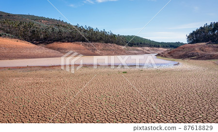 Landscape of low water and dry land in advance, severe drought in the reservoir of Portugal. Ecological disaster, soil dehydration. desert, drought, Landscape of low water and dry land in advance, severe drought in the reservoir of Portugal. Ecological disaster, soil dehydration. desert, drought, 87618829