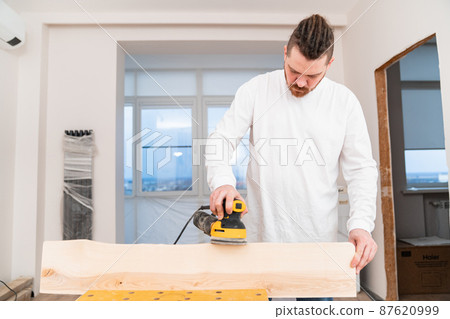carpenter working on wood grinding machine. grinds and polishes wood. carpenter working on wood grinding machine. grinds and polishes wood. 87620999