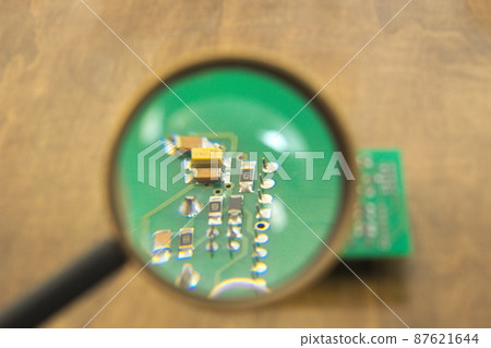 Printed circuit board under a magnifying glass Printed circuit board under a magnifying glass 87621644
